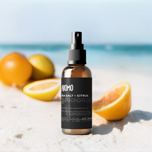 Aromo scents sea salt citrus room spray on a sandy beach with orange and citrus slices